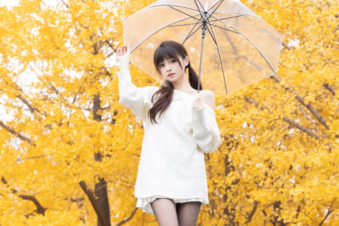 Hetun Nako holding a clear umbrella under golden ginkgo trees