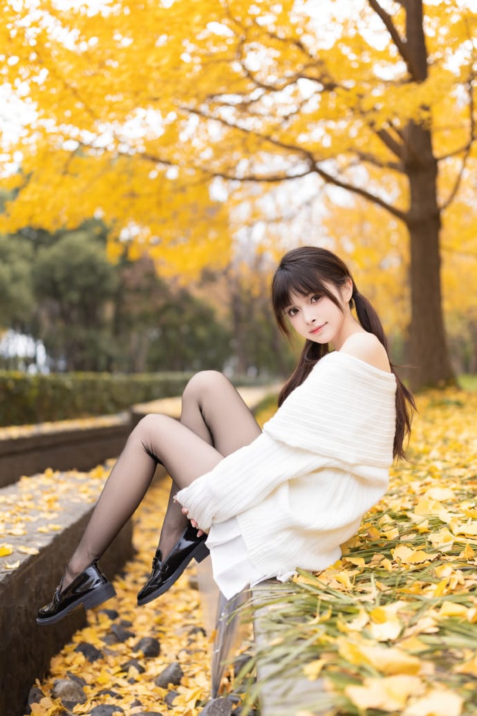 Side profile of Hetun Nako sitting by a stone ledge in an autumn park
