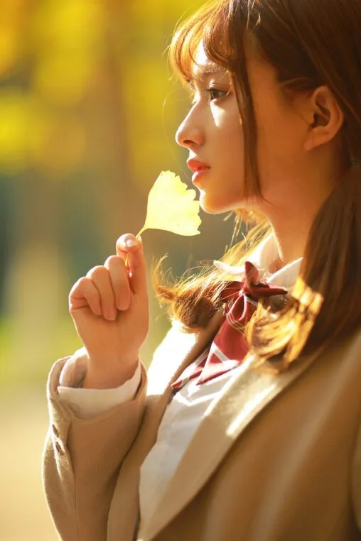 Aesthetic Japanese academy girl holding a golden ginkgo leaf under warm autumn backlight photography by GWJ Wenwen