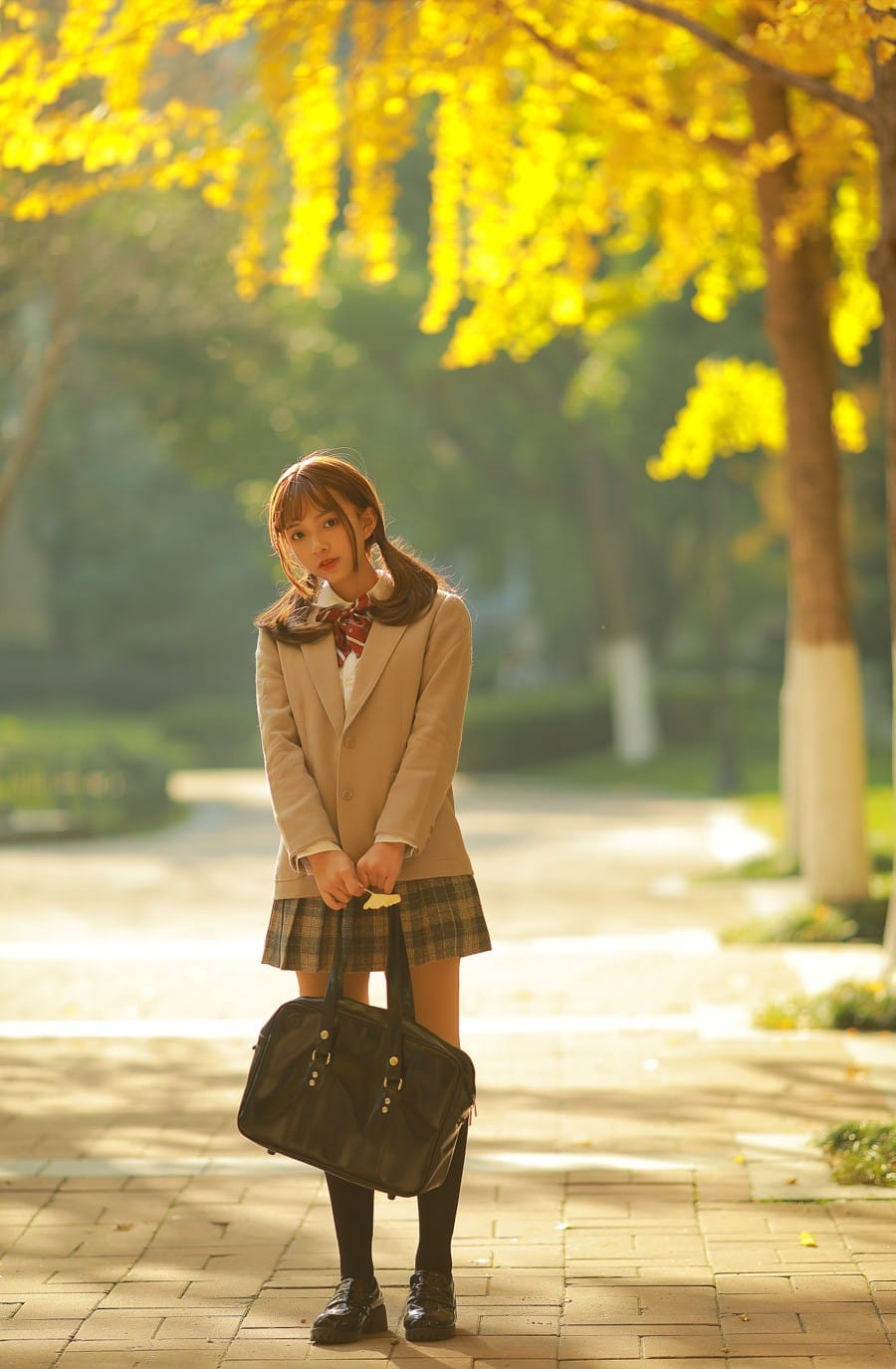 Full length view of a schoolgirl with a bag standing in a golden ginkgo tree avenue photography by GWJ Wenwen
